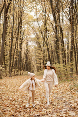 Mother and her daughter playing and having fun in autumn forest