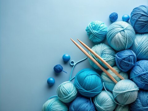 Vibrant blue knitting yarn and needles artfully arranged on a soft light blue background, creating a calming flat lay composition with ample copy space.