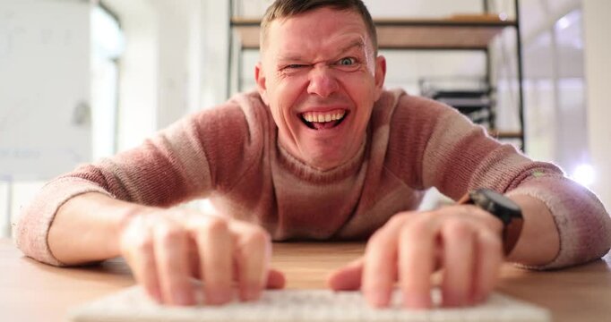 Funny and crazy man using computer uses Internet. Male hands on keyboard and psychopath writes message online