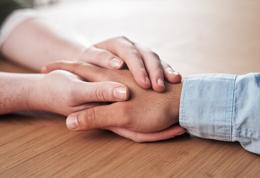 Love, support and people holding hands on table for marriage, kindness and understanding at home. Couple, trust and connection with compassion in commitment for partnership, forgiveness and comfort