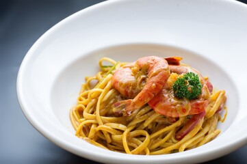 A dish of shrimp pasta garnished with broccoli, served in a white bowl.
