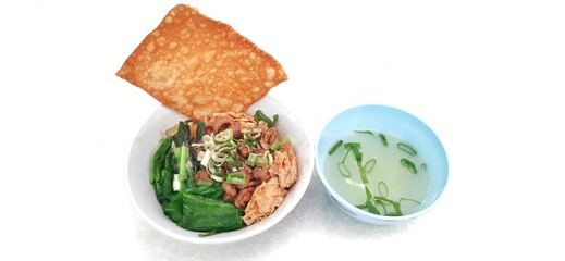 Chicken noodle or mie ayam with fukien, fried dumplings and vegetables served on bowl isolated on white background. Popular street food in Indonesia