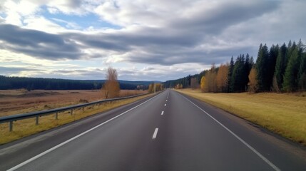 Obraz premium Open Road Ahead: A scenic highway stretches into the distance, bordered by vibrant autumn foliage and a cloudy sky. The road is a symbol of journey, exploration, and the unknown. 