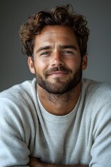 Obraz premium Portrait of a smiling man with curly hair and beard in a cozy sweater