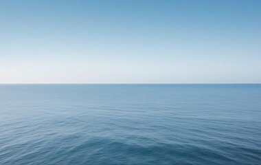Fototapeta premium A tranquil ocean with gentle waves stretching into the horizon. The sky above is mostly blank, offering plenty of copy space.