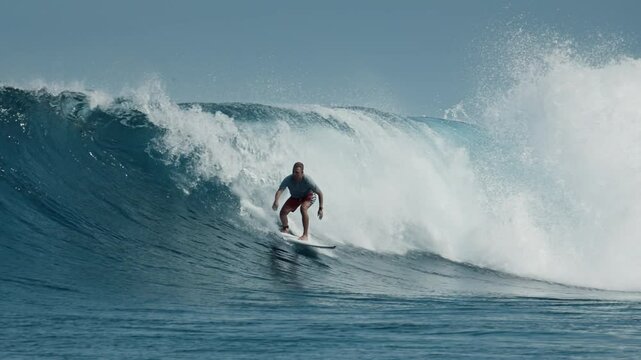 Surfer rides ocean wave in the Maldives, footage has speed warp effect with slow motion