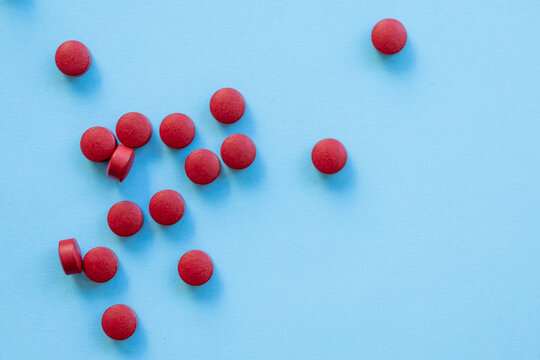 a scattering of red round tablets on a bright blue background