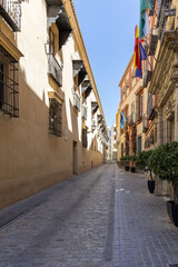 Narrow, picturesque streets of Seville, Spain, featuring colorful buildings, traditional architecture, wrought-iron balconies, and a peaceful urban atmosphere.
