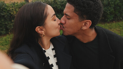 Multiracial couple taking selfie with smartphone in park, showcasing happy moments