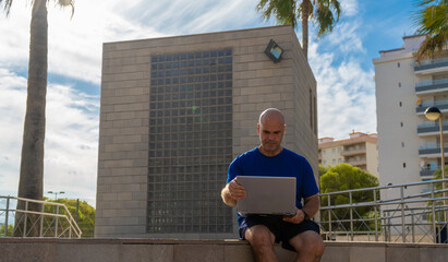 A man working with a laptop sitting in an urban setting, freelancer digital nomad concept.