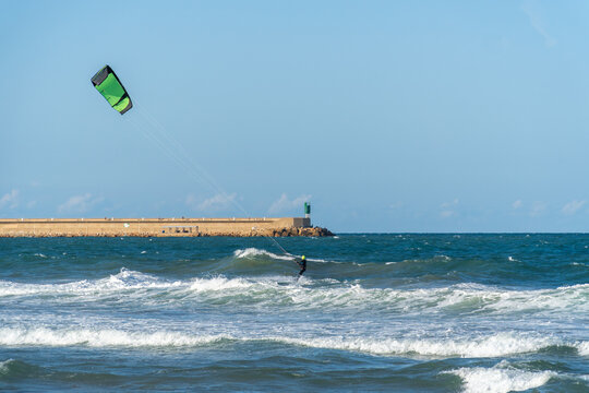 A young man kitesurfing at sunset in the sea.