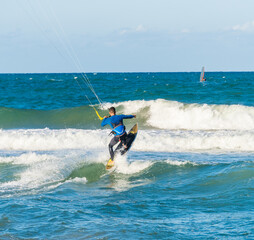 A young man kitesurfing at sunset in the sea.