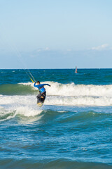 Obraz premium A young man kitesurfing at sunset in the sea.