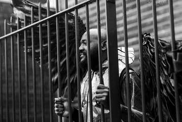 Man with angel wings behind bars in black and white urban scene