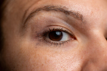 Obraz premium Close-up of a human eye with brown iris and natural skin texture