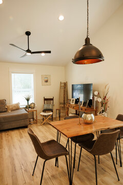 Modern living room with a wooden dining table, black chairs, and pendant lighting complemented by a cozy sofa and television set, Florida, USA