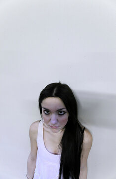 Young woman with dark hair looking up against a pale background, wearing a white sleeveless top, Milan, Italy