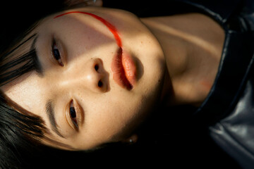 Close-up of a person's face with sunlight casting shadows, featuring a distinct red line across the cheek.