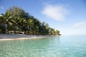 Serene tropical beach with clear blue water, white sand, and abundant green palm trees under a bright sky, Titikaveka, Rarotonga, Cook Islands