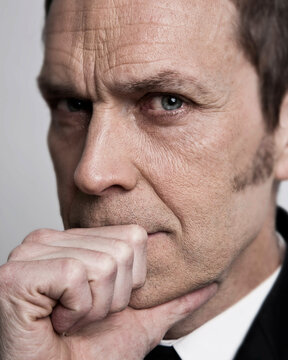 Senior business man looking doubtful into the camera