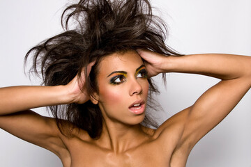 Startled woman with voluminous hair and dramatic makeup posing against a white background.