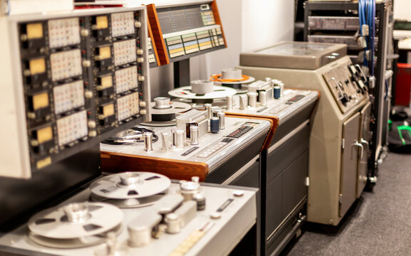 Vintage recording studio equipment with reel-to-reel tape machines and analog sound mixers.