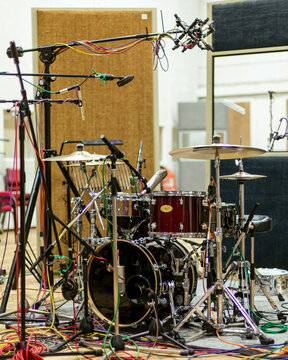 A professional drum set equipped with multiple microphones in a recording studio environment.