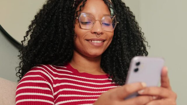 Close-up of happy woman sitting on sofa in living room texting sms using mobile phone