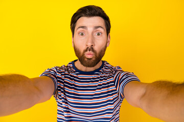Fototapeta premium Portrait of ecstatic funky guy with bristle wear striped t-shirt making selfie pouted lips staring isolated on yellow color background