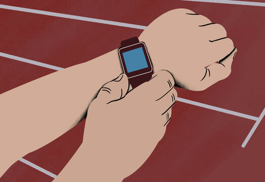 Close-up of a person's hands adjusting a smartwatch against a backdrop of a running track.