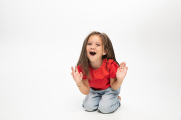 Amased little girl posing on floor, white background. Space for text.