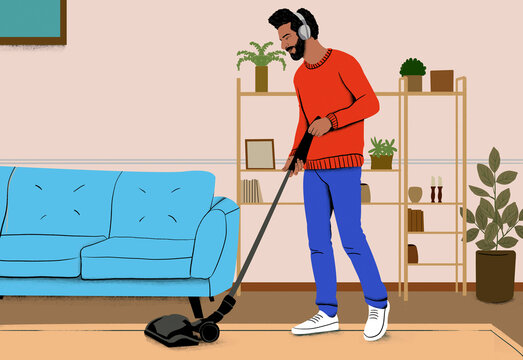 Man in a red sweater vacuuming the living room while wearing headphones.
