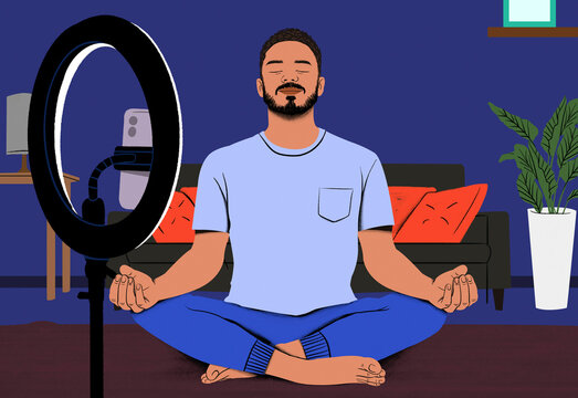 Man meditating in lotus position in a modern room with a ring light and computer setup in the background.