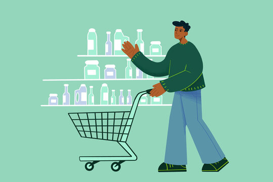 Man with a shopping cart selecting products from a grocery store shelf.