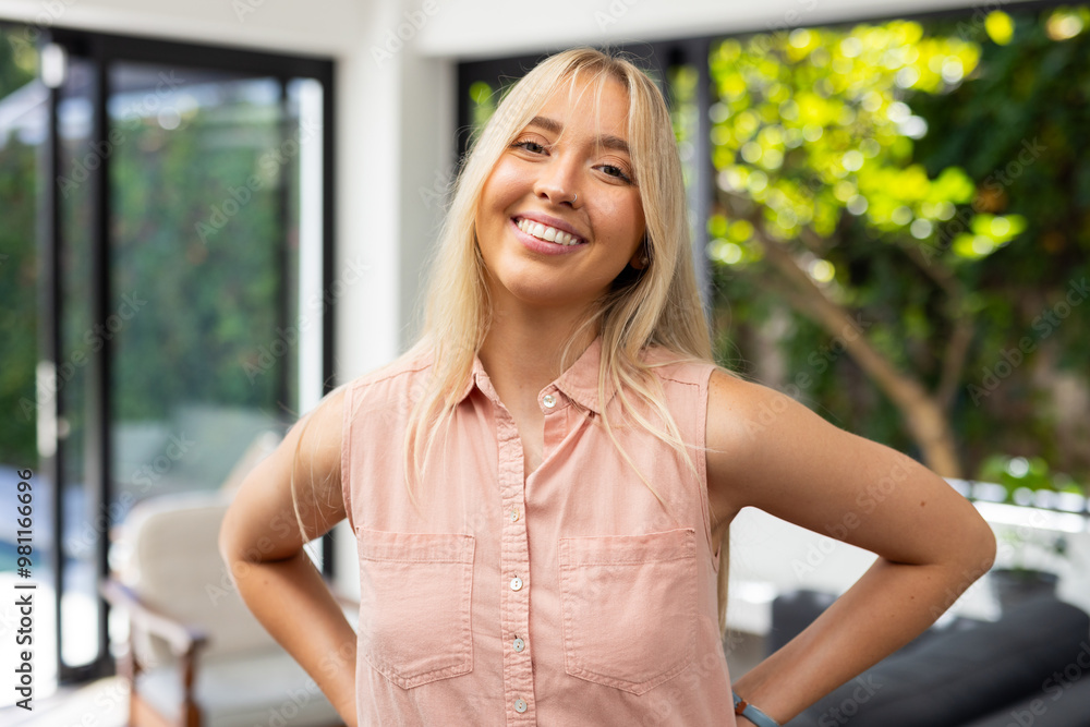 Wall mural smiling woman in casual attire standing confidently in bright living room