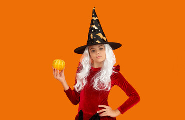 October 31 pumpkin. Costume party. Halloween pumpkin in hand of witch girl. Halloween witch girl isolated on orange. Pumpkin on Halloween. Witch Hallows costume of girl. Traditional Halloween symbol