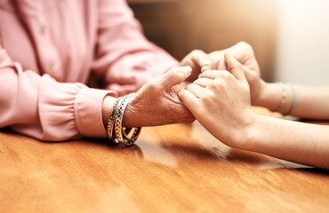 People, holding hands and trust in nursing home for help, empathy or hope in living room. Person, woman or senior care at wooden table for grief counselling, trust or mental health in retirement