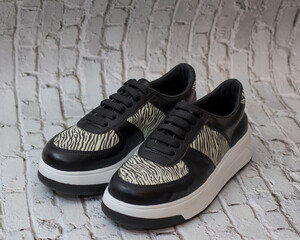 Elegant sneaker in eco-leather, black with animal print motifs, profile view, for casual use