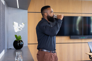 Drinking water, african american businessman taking break in modern office conference room