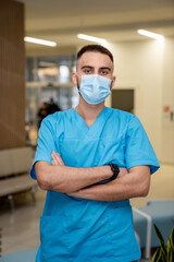 Healthcare worker in blue scrubs indoors. A healthcare professional stands confidently with arms...