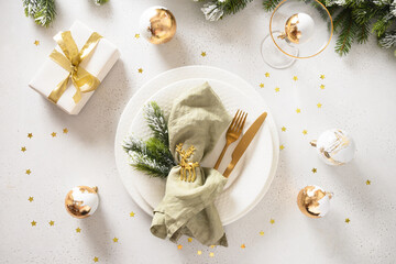 Elegance Christmas table setting with white plate, gift, golden balls on white background. Xmas...