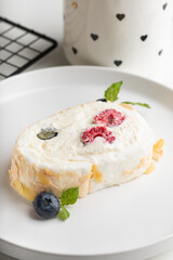 meringue roll with raspberries and blueberries on a white plate