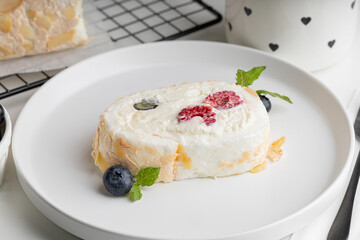 meringue roll with raspberries and blueberries on a white plate