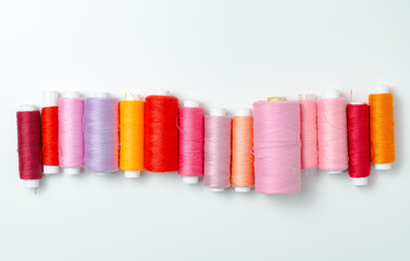 Pink and red thread spools on white background.
