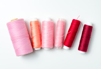 Pink and red thread spools on white background.