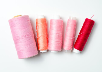 Pink and red thread spools on white background.
