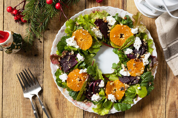 Christmas appetizer New year meal idea. Christmas wreath salad with beetroot, tangerines, feta cheese and pecans on the rustic table.