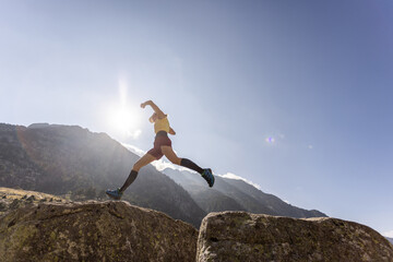 A woman is running up a mountain with the sun shining on her