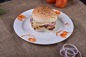 spicy chicken burger with onions pickles and lettuce on a brioche buns
