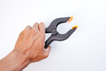 A man's hand is holding a black and orange plastic clamp (screen clamp) on a plain white background